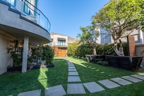 Un bâtiment moderne doté d’un balcon incurvé, d’une pelouse bien entretenue et d’un chemin pavé de pierres.