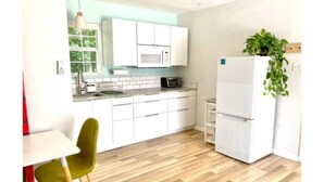 A modern kitchen with white cabinets, a microwave, a toaster, and a refrigerator. There is a green chair and a plant on the counter. - 🌿Peaceful Poolside Bungalow in Backyard Oasis🌿 (Austin)