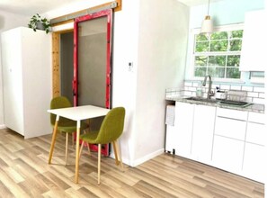 A kitchen with a white countertop, a sink, and a window with a view of greenery.