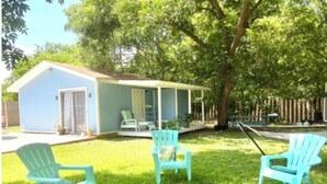 A house with a porch, three Adirondack chairs, and a fire pit. - 🌿Peaceful Poolside Bungalow in Backyard Oasis🌿 (Austin)