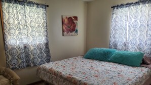 Une chambre à coucher avec une couvre-lit à motifs floraux, un coussin turquoise et un tableau accroché au mur.