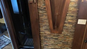 A wooden door with a stone wall and a glass door leading to a room. - Large farm house in country setting. Wrap around decks, luxury vinyl plank throughout with washer/dryer and huge game room. 5 bedrooms, plenty of room to stretch out and relax. Large pool is available end May - end September. (Greenwood)