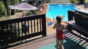 A backyard with a swimming pool, surrounded by trees and a wooden deck. - Large farm house in country setting. Wrap around decks, luxury vinyl plank throughout with washer/dryer and huge game room. 5 bedrooms, plenty of room to stretch out and relax. Large pool is available end May - end September. (Greenwood)