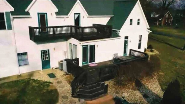 A two-story house with a front porch and a small garden area. - Large farm house in country setting. Wrap around decks, luxury vinyl plank throughout with washer/dryer and huge game room. 5 bedrooms, plenty of room to stretch out and relax. Large pool is available end May - end September. (Greenwood)