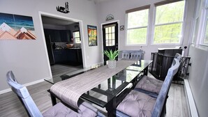 A dining area with a glass-top table, cushioned chairs, and a potted plant.