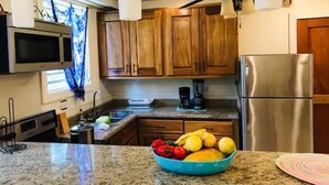 A kitchen with wooden cabinets, a stainless steel refrigerator, a microwave, and a coffee maker.