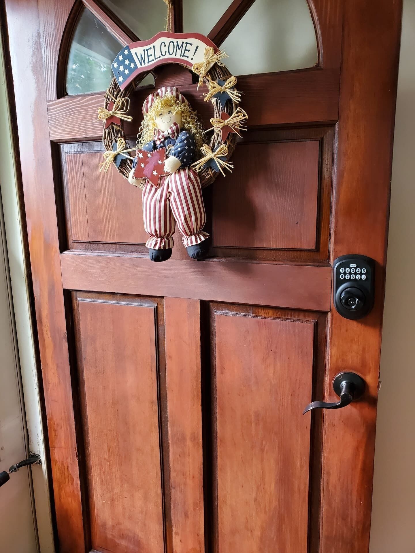Une porte en bois ornée d’une pancarte de bienvenue et d’une figurine décorative.