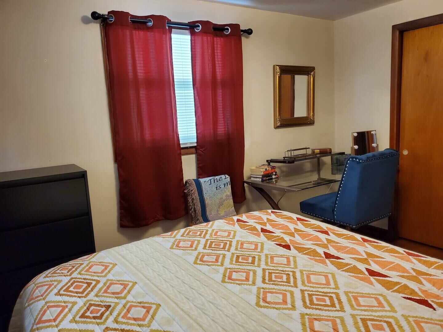 Une chambre à coucher avec un lit, un bureau, une chaise et un miroir.