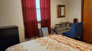 Une chambre à coucher avec un lit, un bureau, une chaise et un miroir.