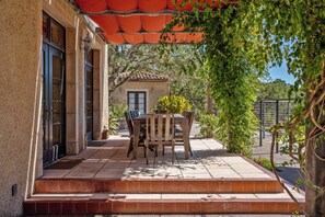 A patio with a wooden table and chairs, a tiled floor, and a red awning. - Entire villa in Hopland, California (Hopland)