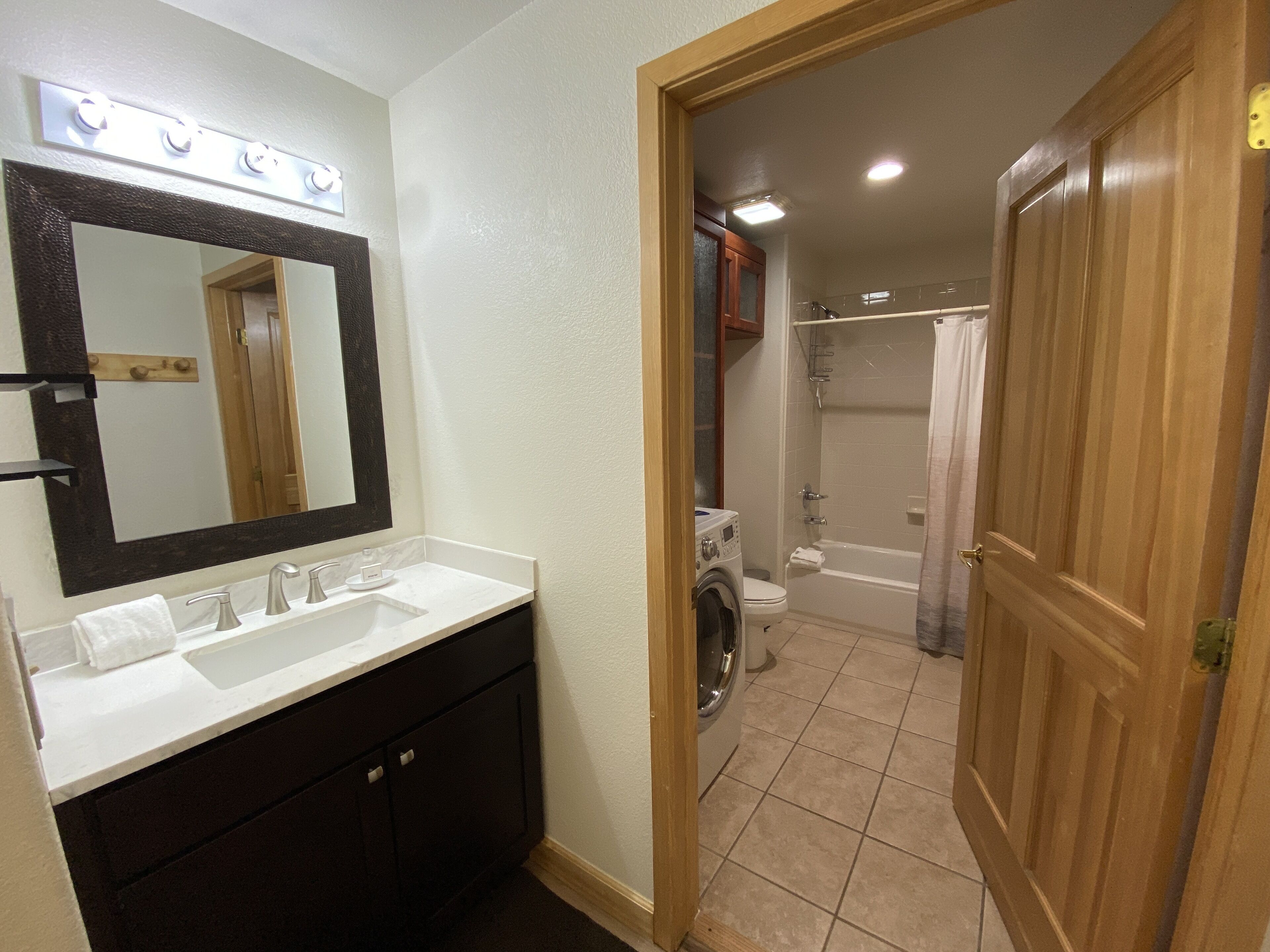 A bathroom with a sink, mirror, and a shower area.