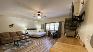 A hotel room with a bed, sofa, dining table, and a TV mounted on the wall. - Gateway Lodge 5037 (Keystone)