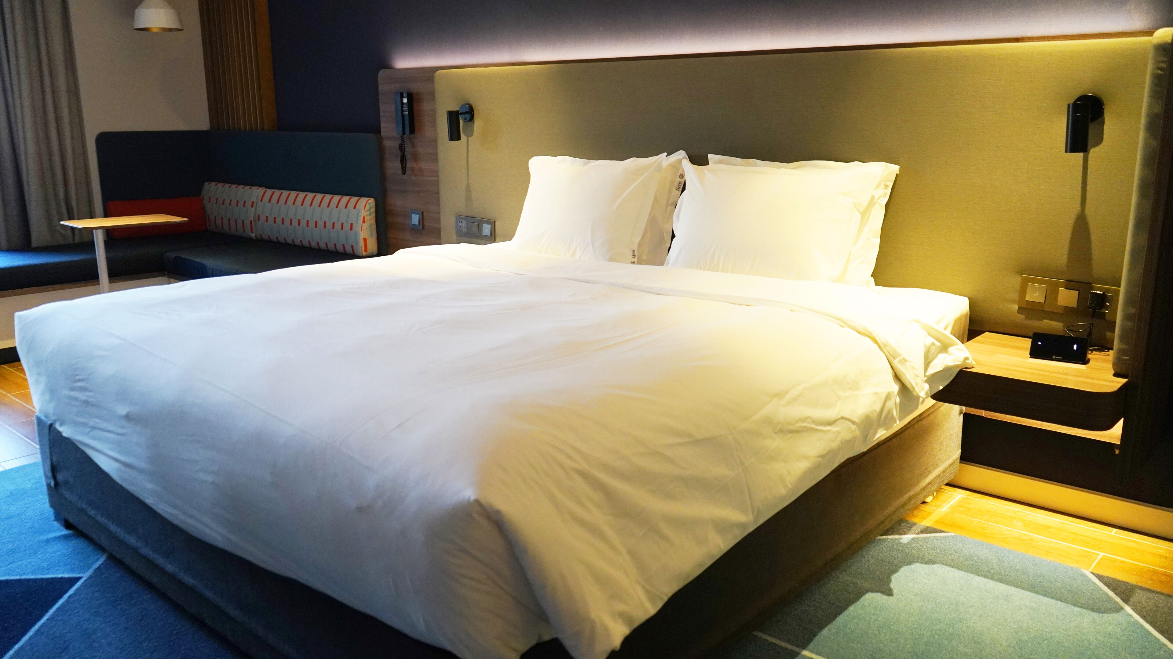 Una habitación de hotel con una cama grande, mesitas de noche, un sofá y una lámpara.