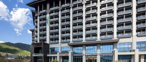 A modern hotel building with multiple balconies, a tourist center, and a sign for Holiday Inn Express.