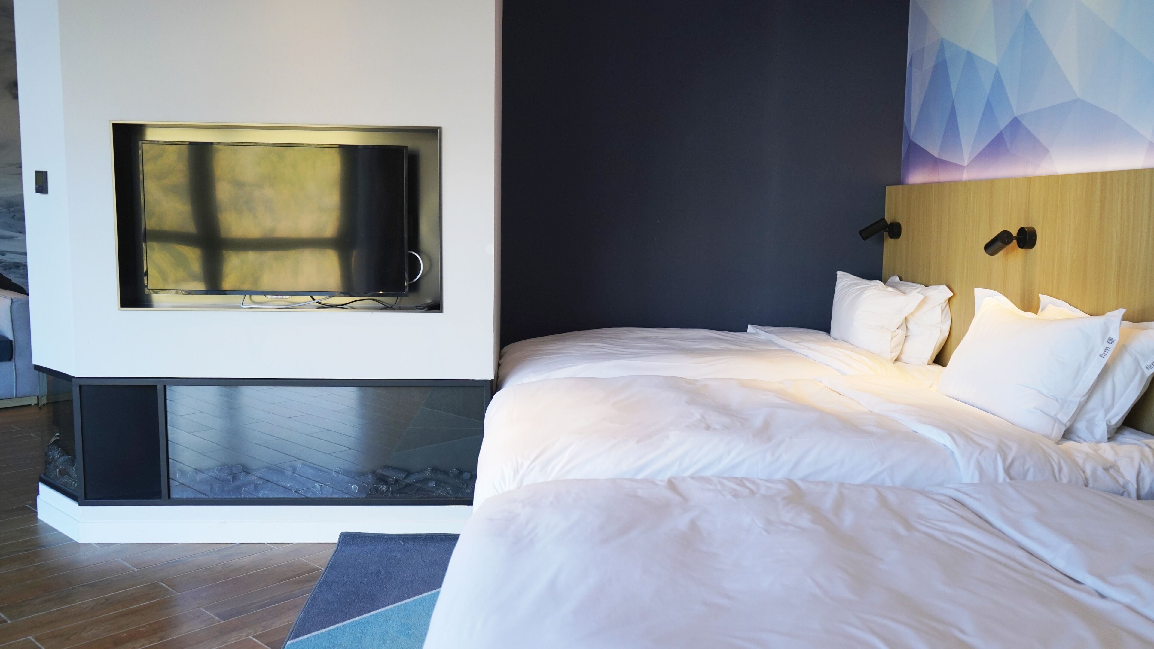 A modern bedroom with a large bed, a built-in TV, and a wooden headboard.