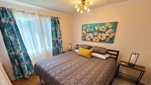 A bedroom with a bed, a nightstand, a painting, and a window with curtains.