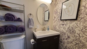 A bathroom with a toilet, sink, towel rack, and a mirror.