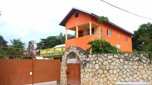 Un edificio de dos pisos con un muro de piedra y una verja metálica.