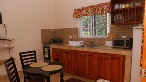 Una cocina compacta con una mesa de comedor, sillas, microondas y refrigerador.