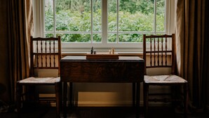 Une pièce avec une fenêtre, deux chaises en bois, une table et un jeu d’échecs.