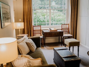 Una sala acogedora con un sofá, dos sillones, una mesa de madera y una ventana con cortinas.