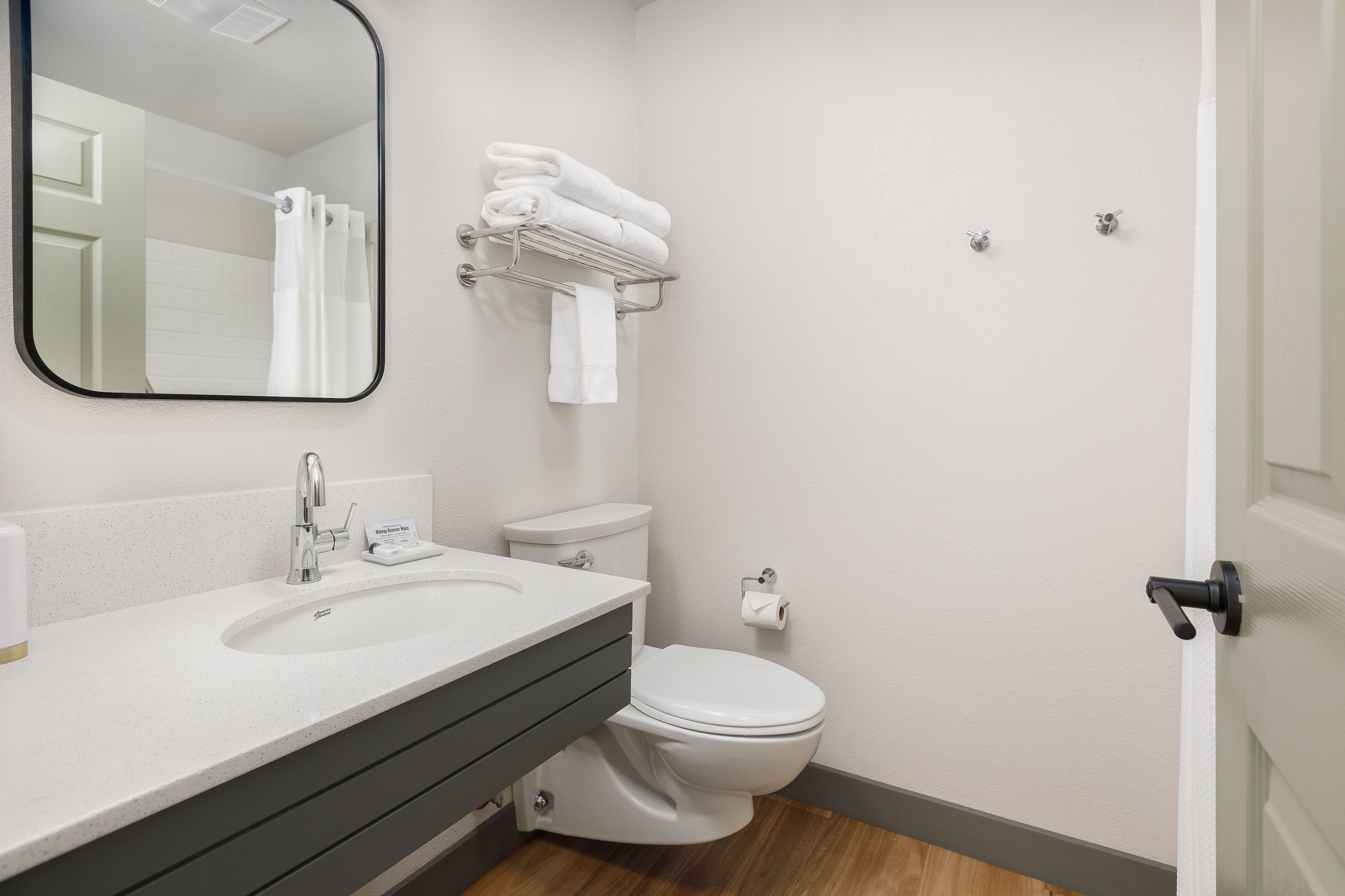 Een moderne badkamer met een wit wastafel, toilet en handdoekhouder.