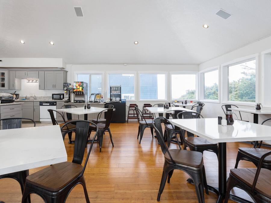A spacious kitchen with modern appliances, large windows, and a dining area with multiple tables and chairs.