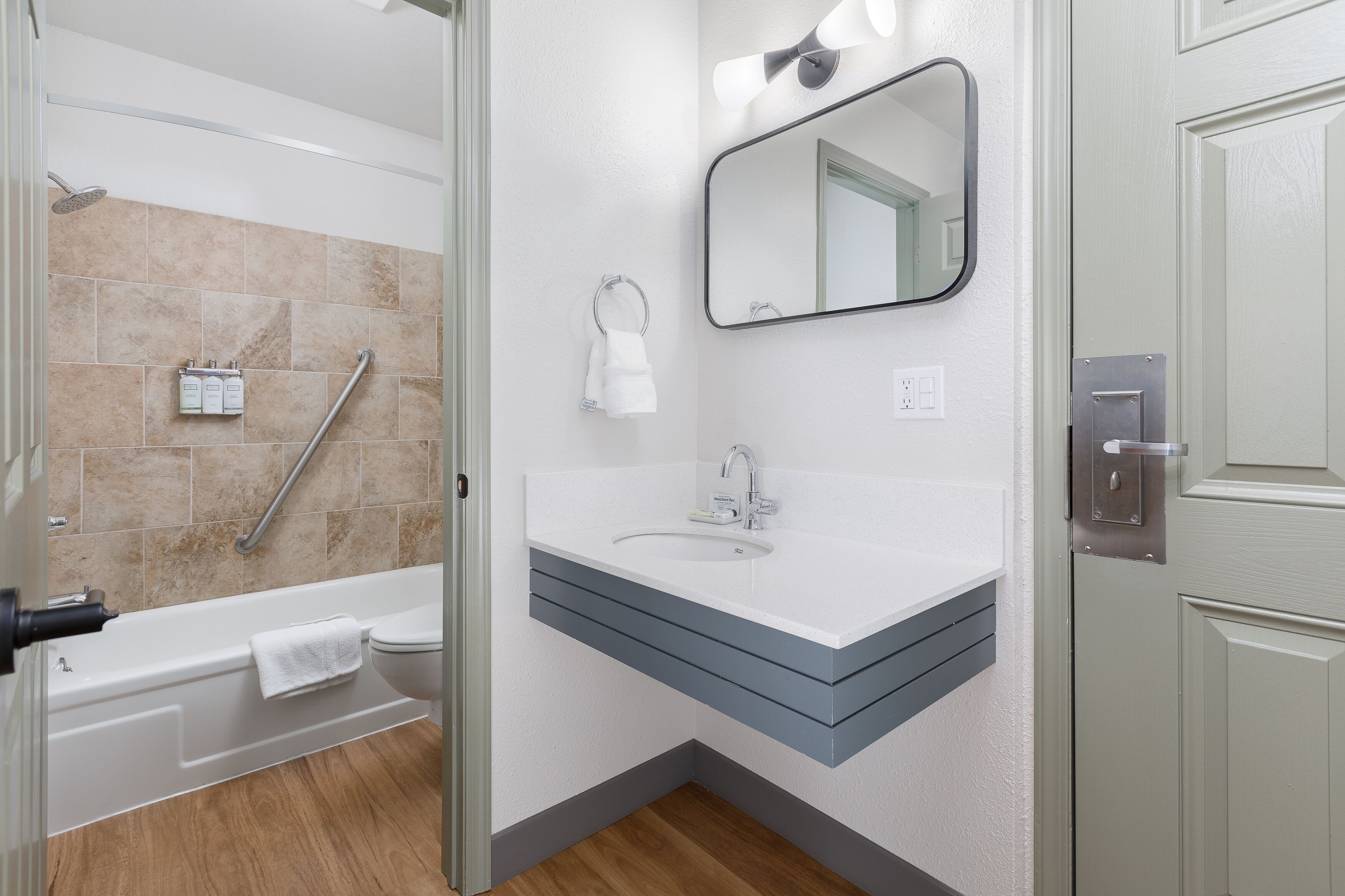 Une salle de bain moderne avec un lavabo blanc, un miroir et des carreaux de couleur beige.