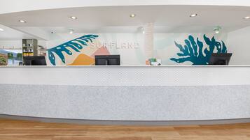 A reception area with a modern design, featuring a large, colorful mural and a counter with a digital display.