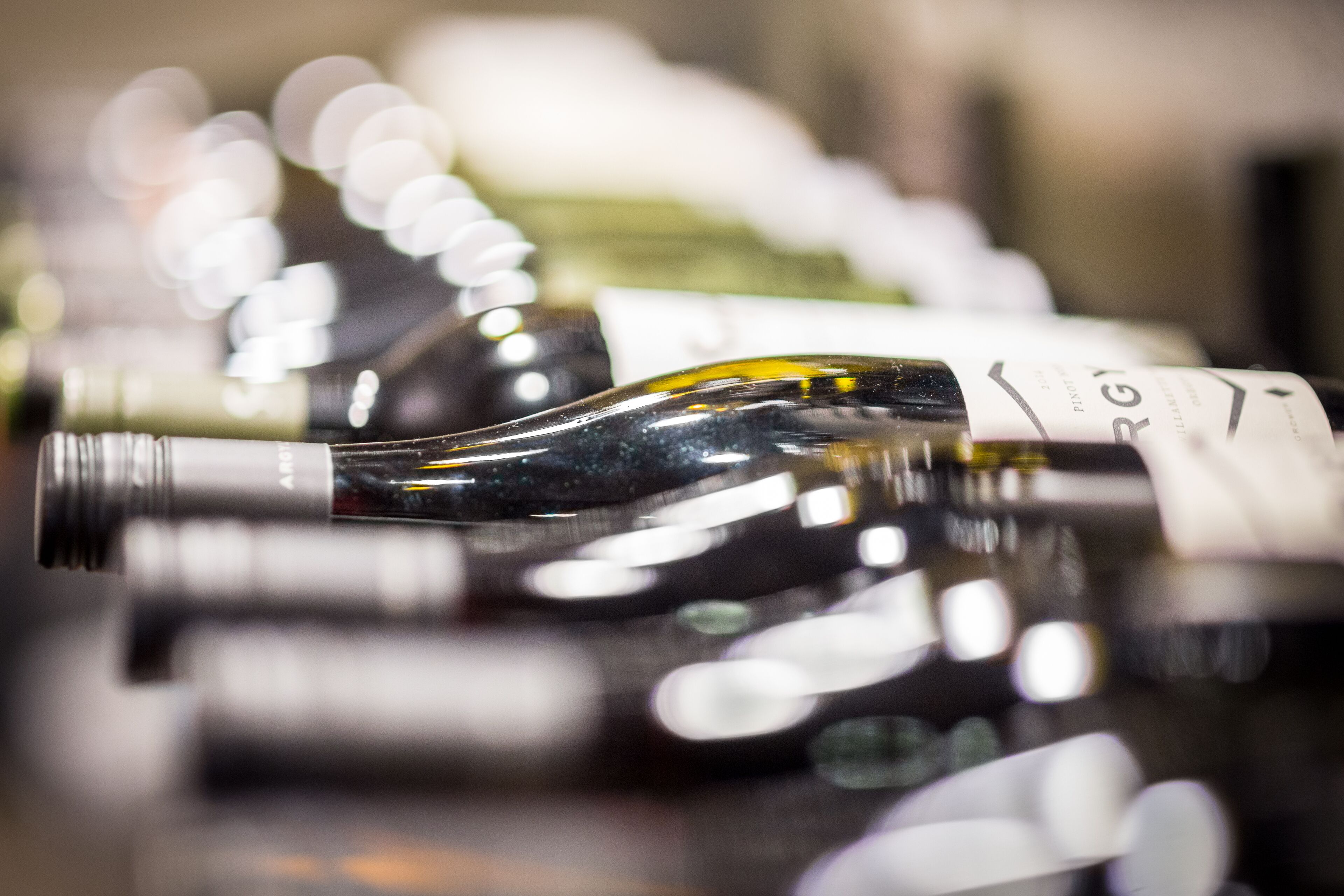 A collection of wine bottles with labels, arranged closely together.