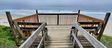 A wooden staircase leading to a beach with a view of the ocean.