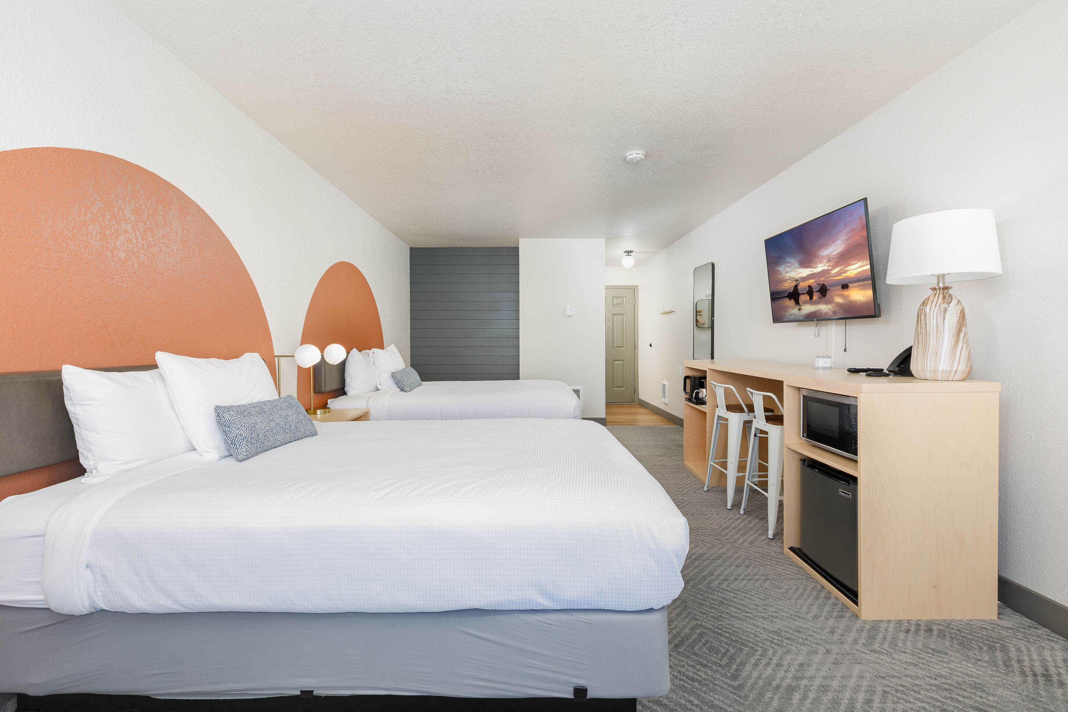 Ein Hotelzimmer mit zwei Betten, einem Schreibtisch mit Computer, einem Fernseher und einer Lampe.