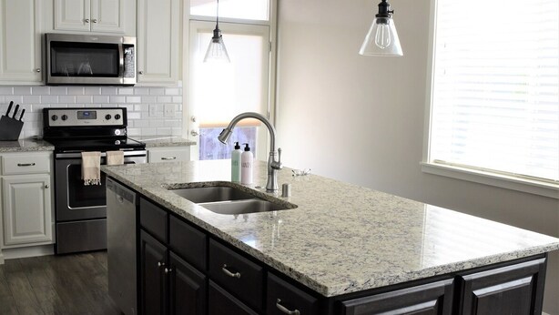 A kitchen with white cabinets, a granite countertop, a stainless steel sink, a microwave, an oven, and a pendant light. - Stylish modern home- explore PNW Hike work from home or explore nearby wineries  (Battle Ground)
