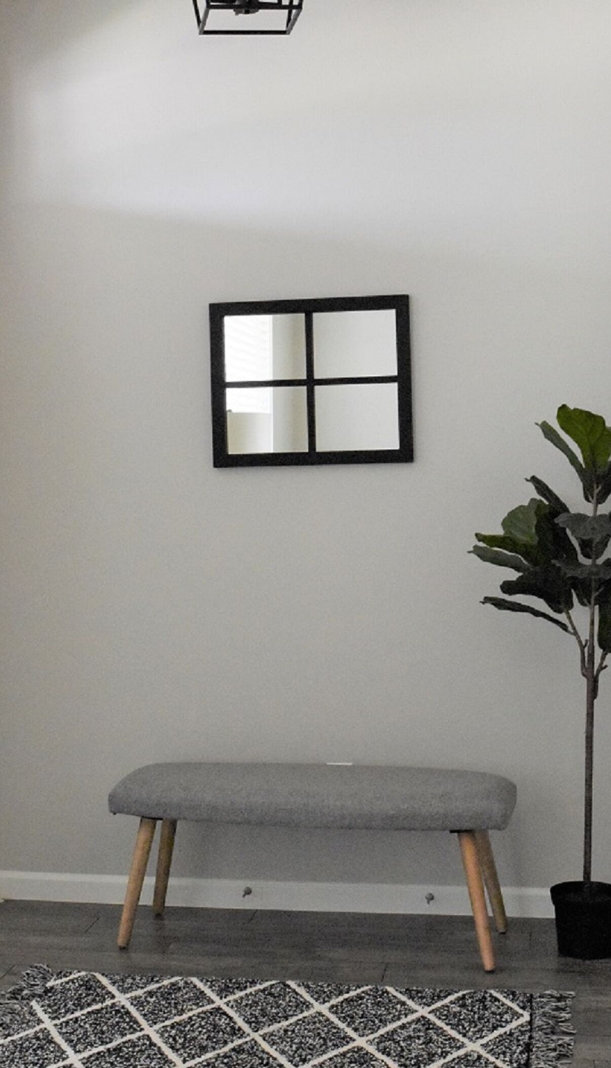 Ein Zimmer mit einer Bank, einem Blumentopf und einem Wandspiegel.