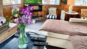 A cozy room with a TV, a chair, a couch, and a vase of flowers. - Bodega Bay - Sonoma Coastline (Bodega Bay)