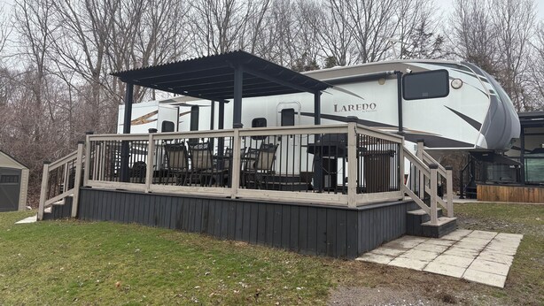 Un véhicule récréatif doté d’une terrasse couverte et d’un espace salon extérieur.