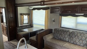 Un intérieur de camping-car compact comprenant un coin cuisine, un espace repas et un coin salon.