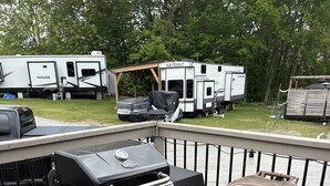 Un barbecue installé sur une terrasse extérieure, avec une poubelle et une table de préparation couverte à proximité.