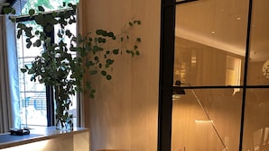 A modern interior with a wooden bench, a large potted plant, and a patterned floor. - The Moore, a Member of Design Hotels (New York)