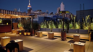 A rooftop terrace with seating areas, a coffee table, and a decorative lamp. - The Moore, a Member of Design Hotels (New York)