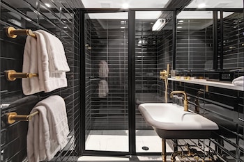 A reception desk with a modern design, a framed artwork on the wall, and a window with curtains. at The Moore, a Member of Design Hotels