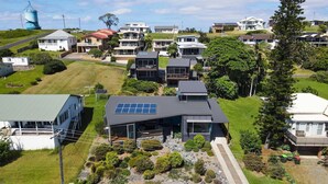 A residential area with modern houses, solar panels, and a water tower in the background. - Rock Ledge - Woolgoogla Headland (Woolgoolga)