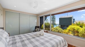 A bedroom with a large bed, a view of the ocean, and a sliding door closet. - Rock Ledge - Woolgoogla Headland (Woolgoolga)