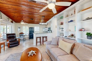 Relax in this stylish living area with a high ceiling, comfortable sofa, and wooden coffee table.