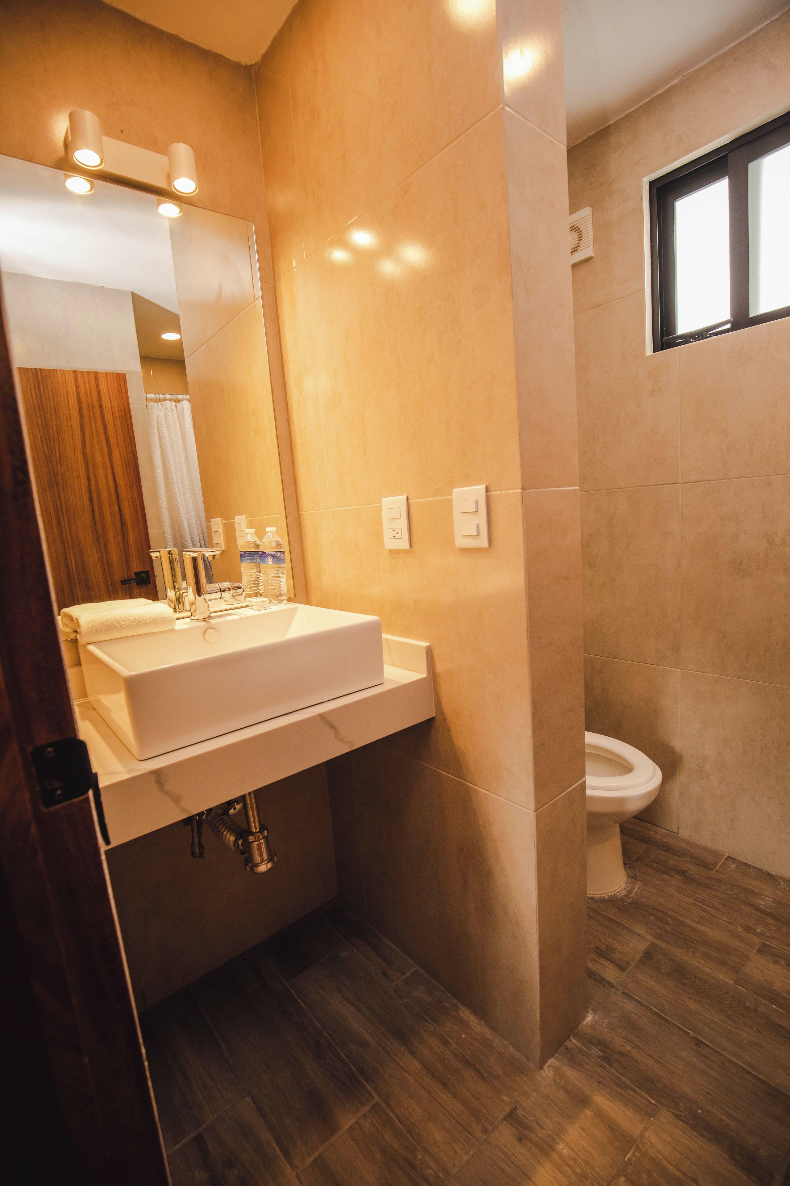 Un baño moderno con lavamanos grande, espejo e inodoro.