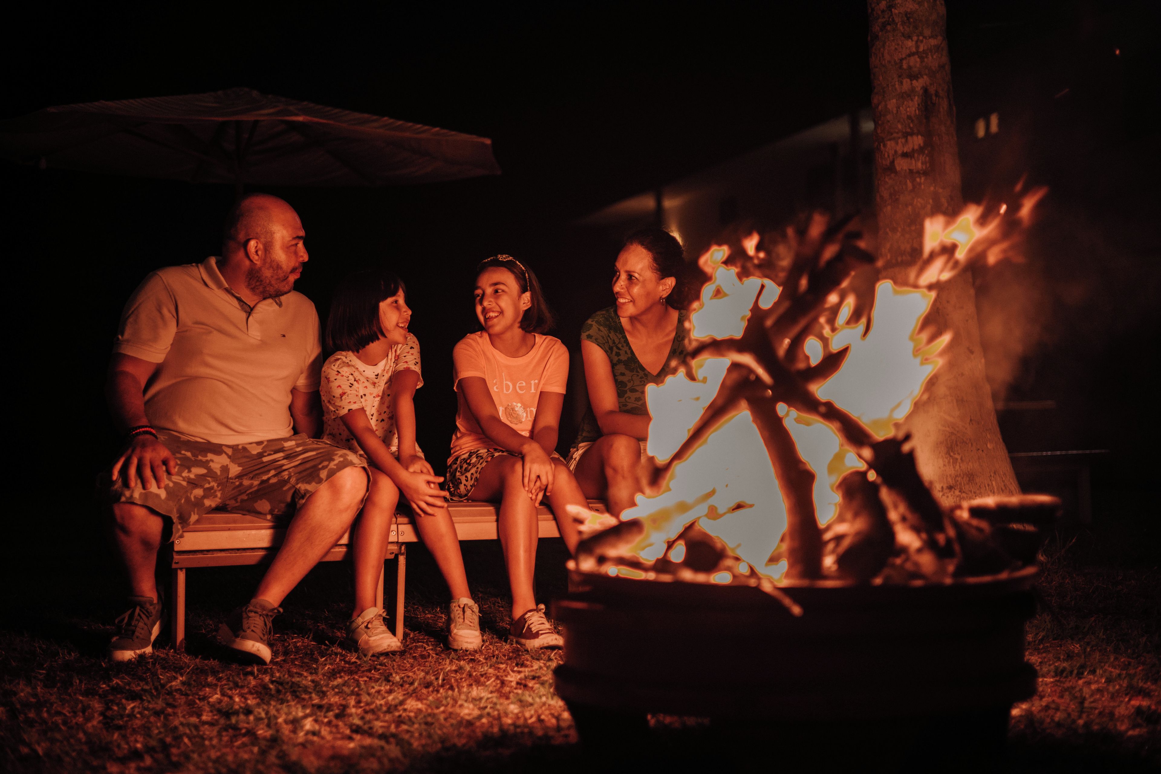 A group of people sitting around a campfire at night.