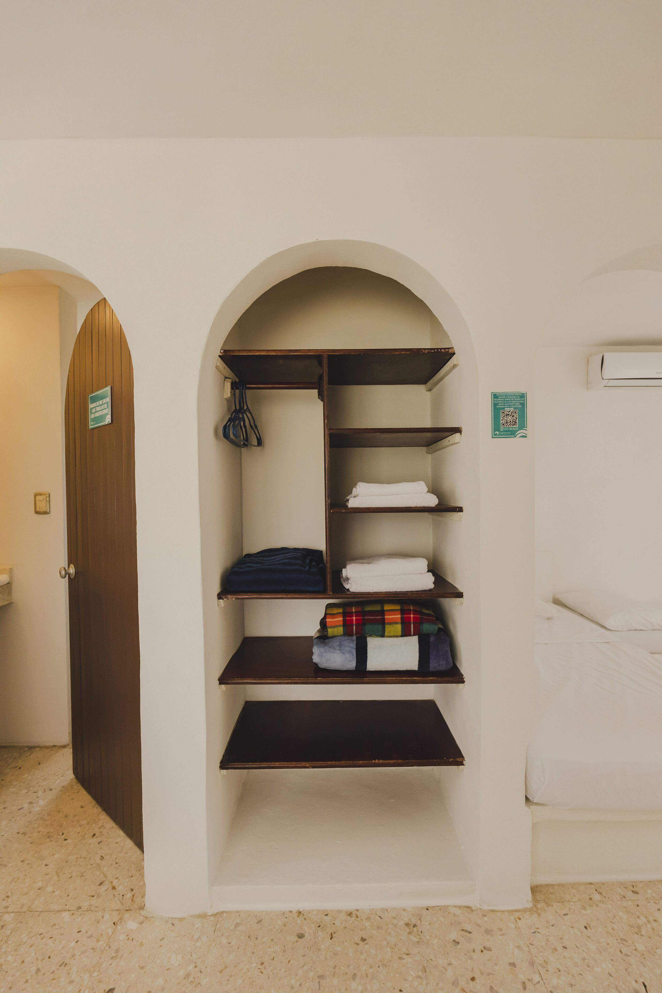 A hotel room with a built-in wardrobe, a bed, and a small seating area.