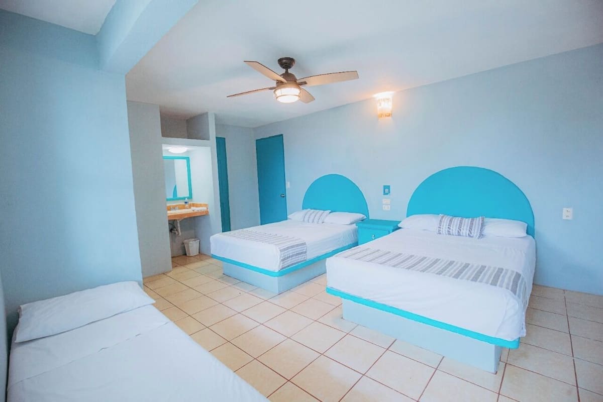 A hotel room with two beds, a ceiling fan, and a bathroom visible through an open door.