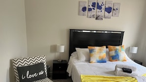 A hotel room with a bed, a chair, a nightstand, and a lamp.