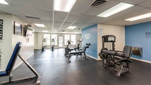 A gym with exercise equipment, a blue wall, and a sign that says "EVEN IS AS WELL AS."
